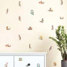 Load image into Gallery viewer, Wall with decorative stickers of animals and plants, a white cabinet, and a plant on a black table.
